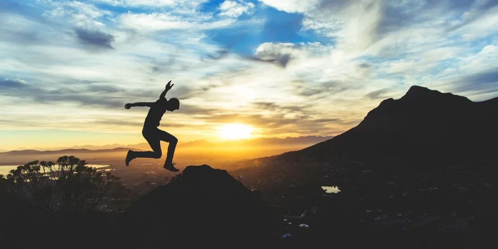 a man jumping silhouetted by sun