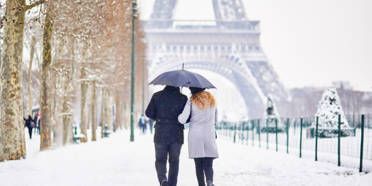 A couple strolling in the snow under the Eiffel Tower