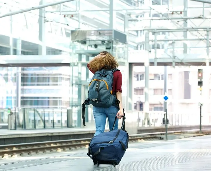 overnight train tips - girl pulling luggage along train platform