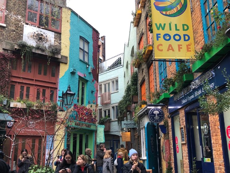 A picture showing people walking next to painted buildings in Neal's Yard London