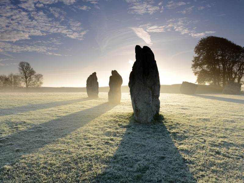 Three large stones standing in a misty field