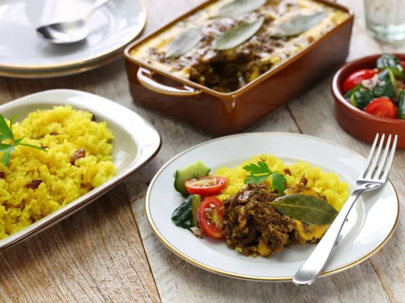 Bobotie on a plate with some rice in a bowl a popular South African food