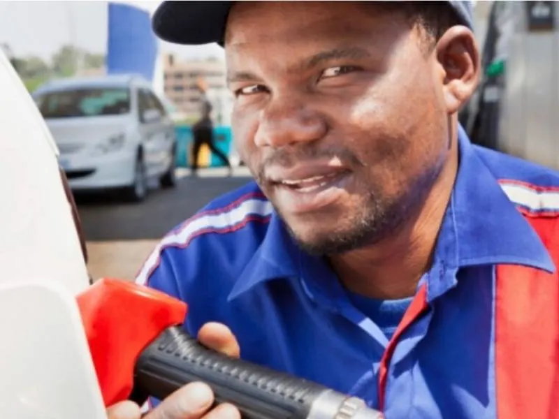 A petrol attendant putting petrol in a car