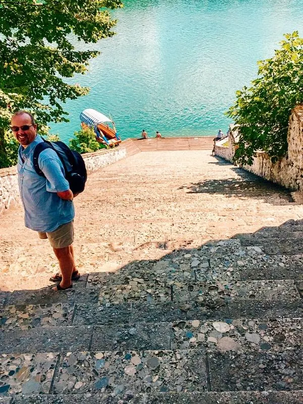 A man standing on stone steps on an island in Lake Bled.