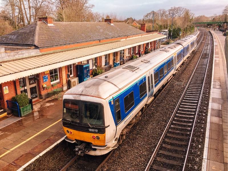 Train passing through a train station as seen from a bridge above the platform