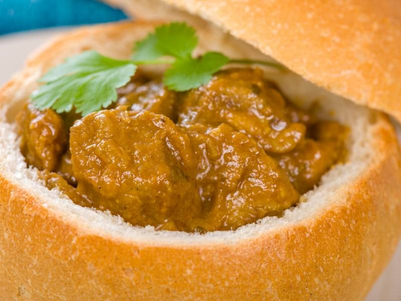 A bread bun with curry inside one of many traditional South African foods