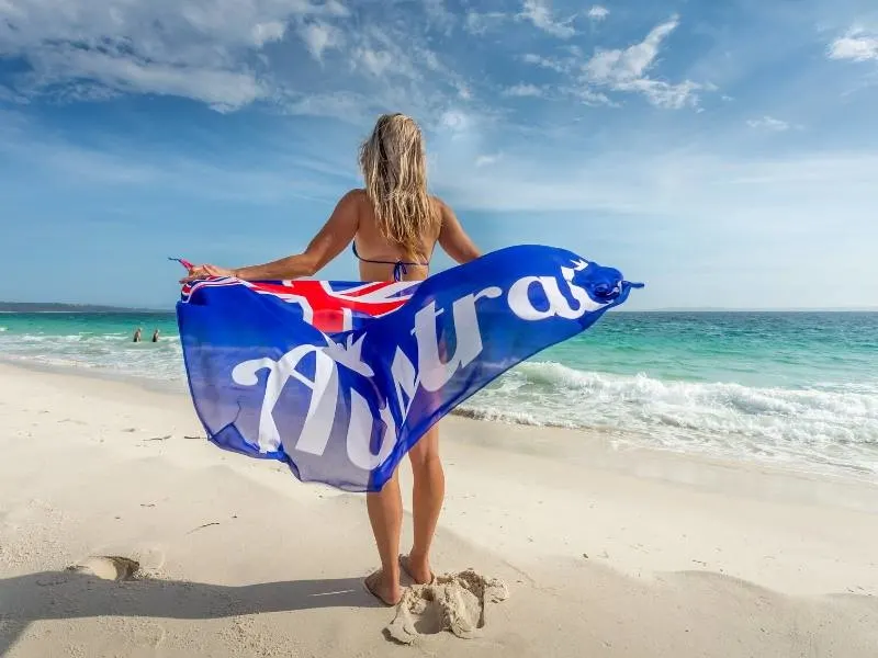 A woman standing on a beach holding an Australian flag