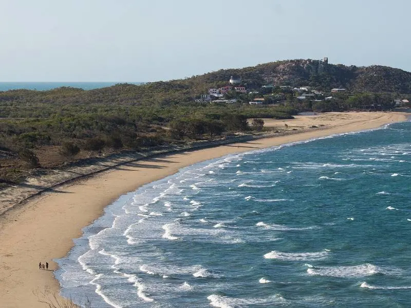 A bay and a beach fringed by trees