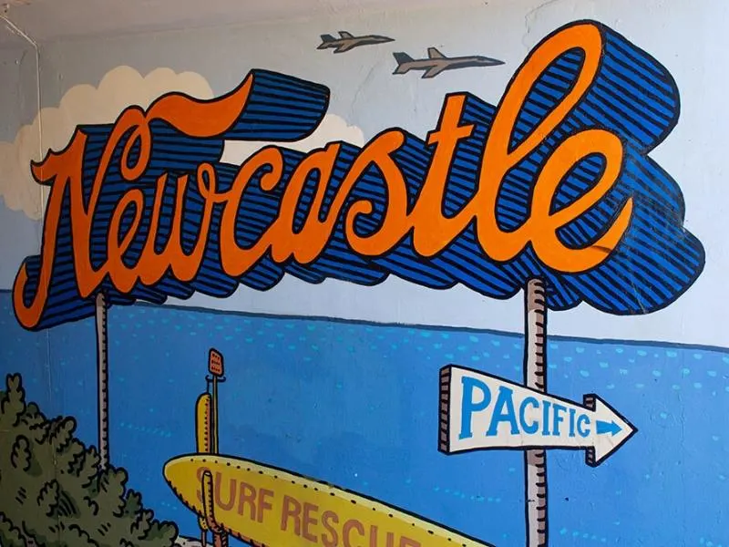 Mural of the word Newcastle with a surf board and sign for the Pacific