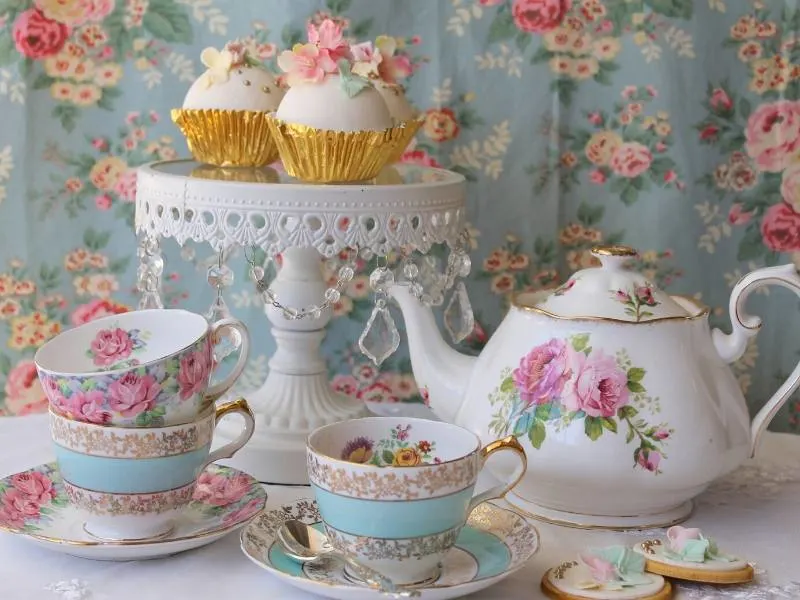 A teapot with teacups, saucers and cakes