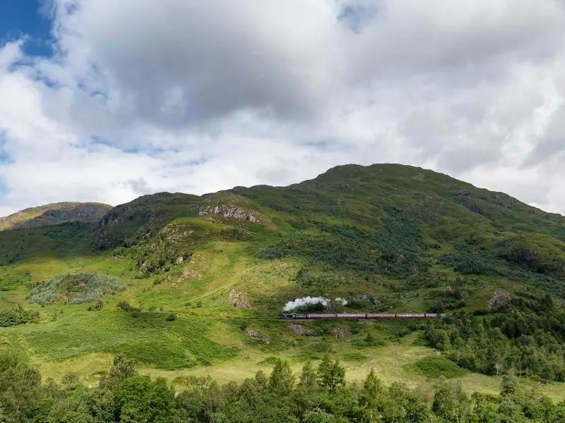 Steam train crossing green countryside in Scotland