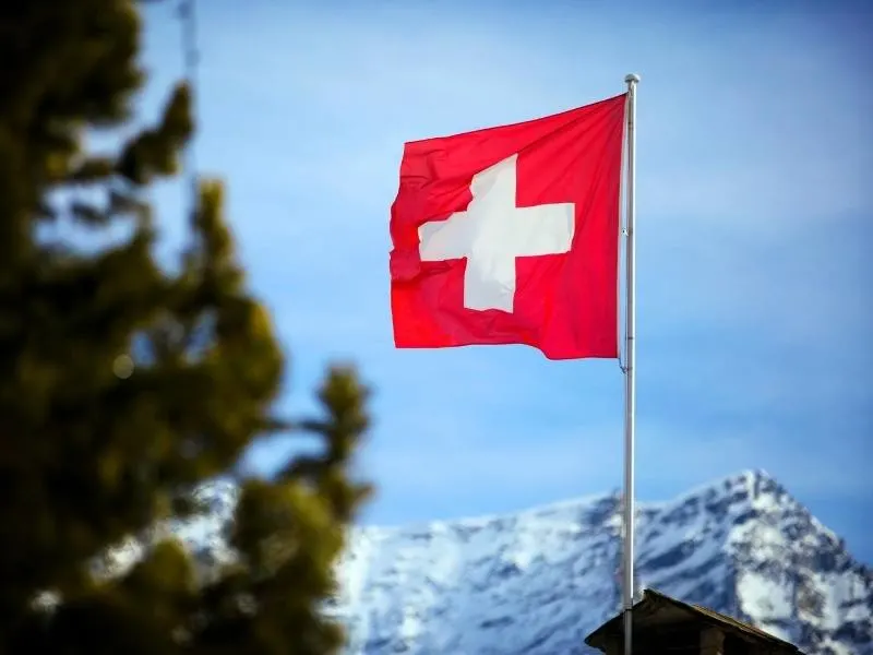 The Swiss flag with mountains in the background