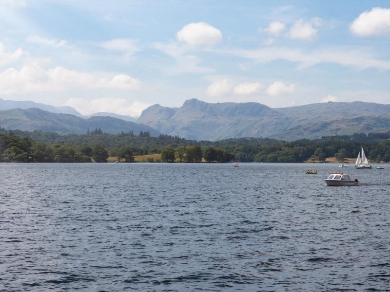 View of a lake with a boat crossing and hills in the background