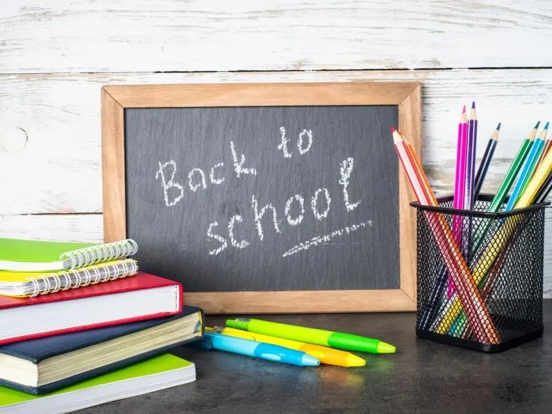 Back to school sign and lots of pens and pencils - support children emigrating by enrolling them in school quickly