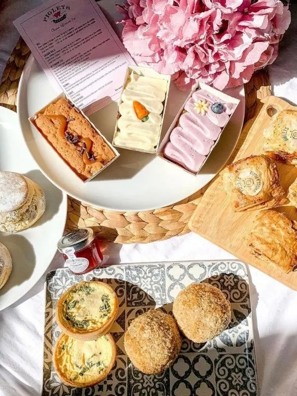 An afternoon tea in a box from Piglet's Pantry laid out on plates with a pink flower.