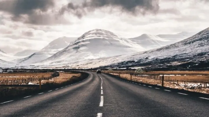 A road surrounded by snow covered mountains