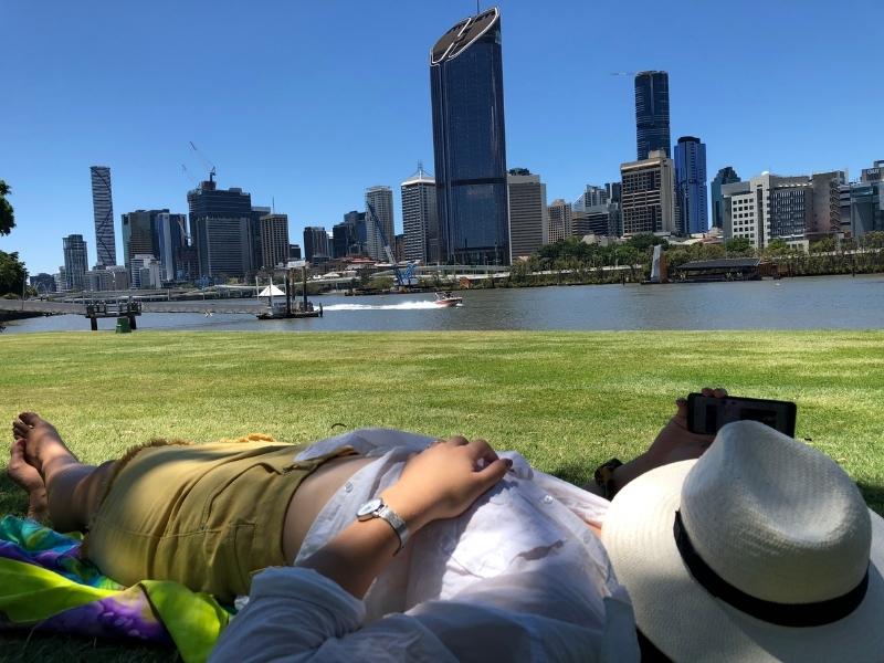 A view of Brisbane from South Bank and a girl relaxing enjoying the view.