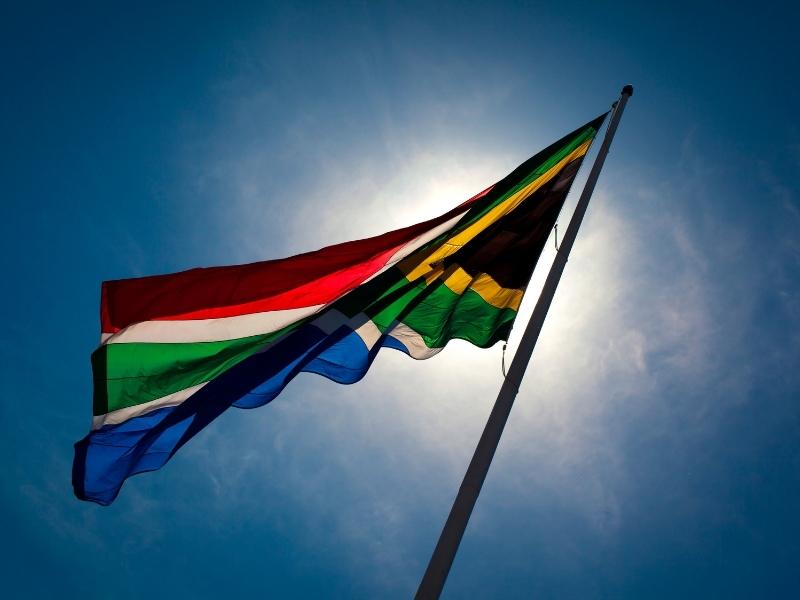 South African flag silhouetted against a blue sky.