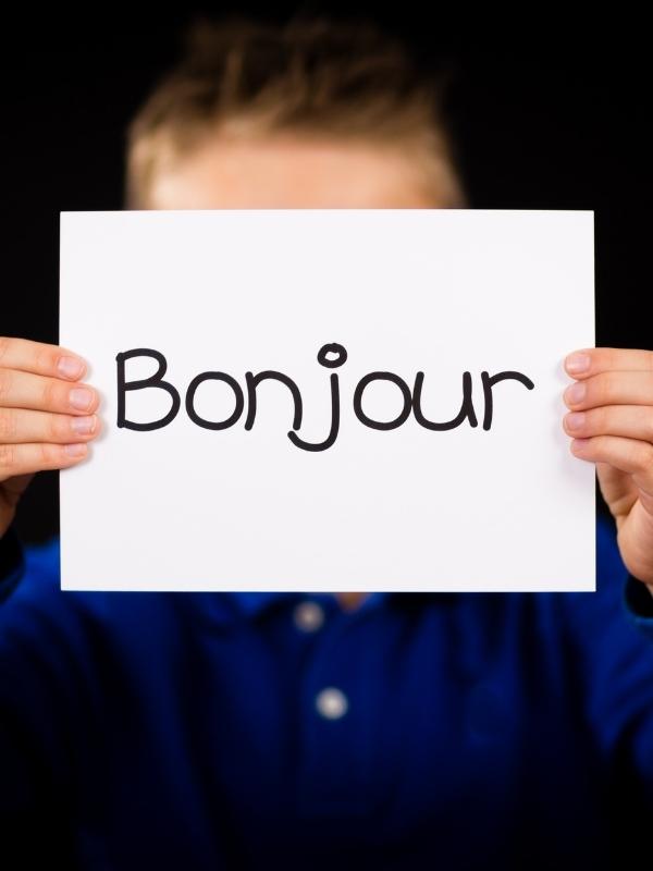 Boy holding a sign saying Bonjour.