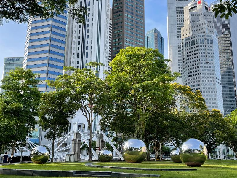 Large stainless steel ball sculptures against a backdrop of the Singapore skyline.