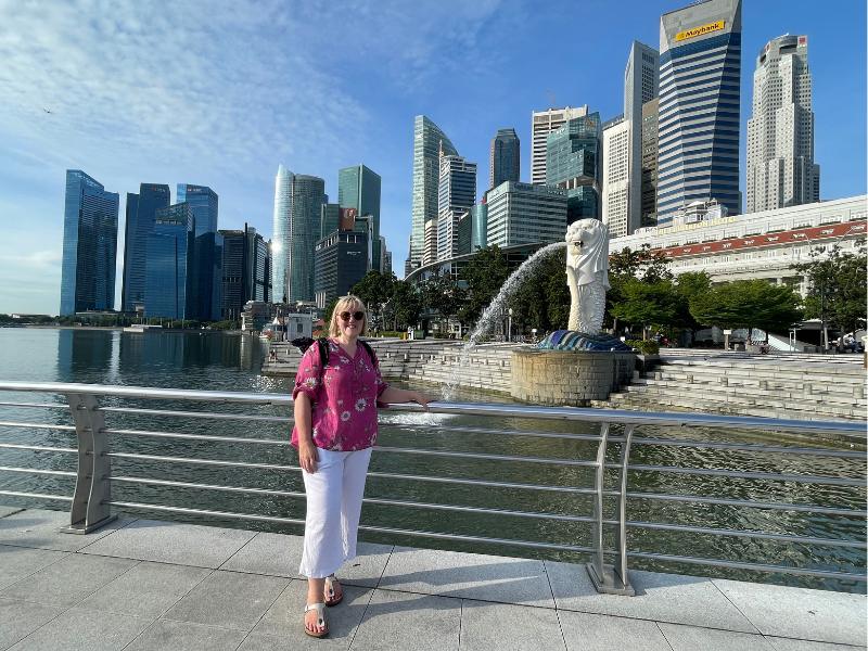 Tracy Collins standing in front of the Merlion in Singapore.