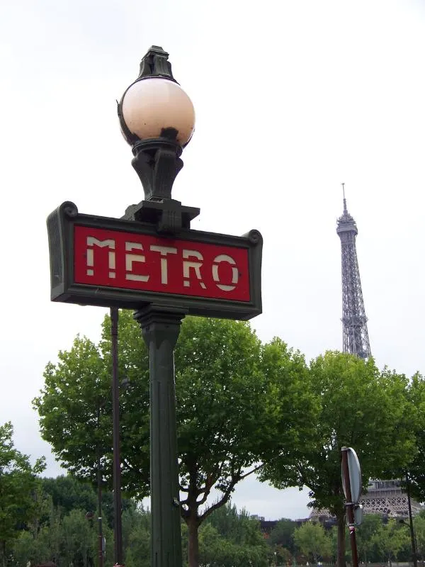 Metro sign in Paris with the Eiffel Tower behind.