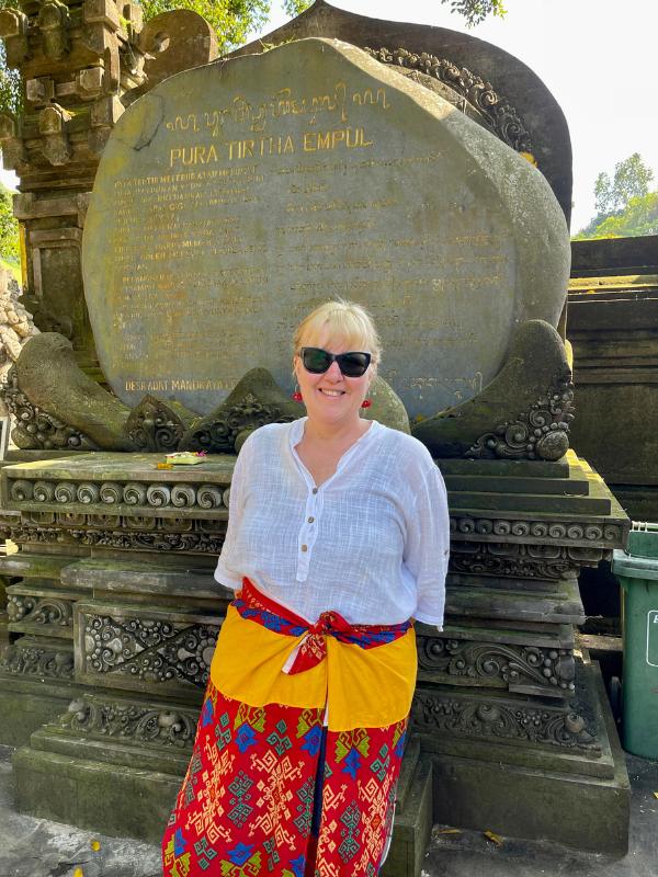 Bali travel tips include wearing appropriate clothing in temples such as a long skirt worn by the lady in this image.
