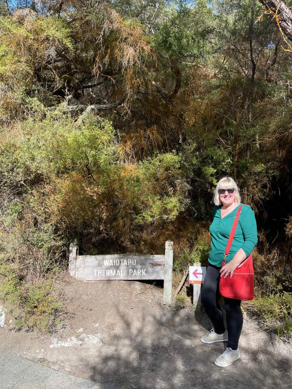 Tracy Collins standing at the sign for Waiotapu Thermal Park.