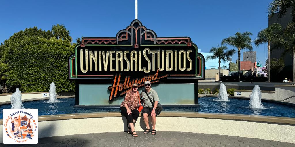 Man and woman beneath a sign for Universal Studios LA