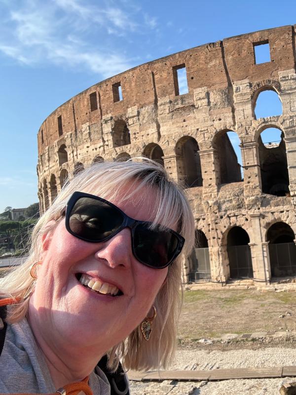 Lady smiling in front of the Colossuem.