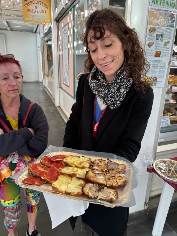 A woman holding a tray of pizza.