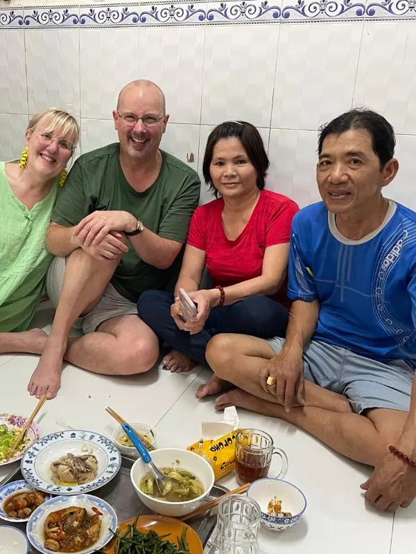 Four people sitting on the floor with food in front of them.