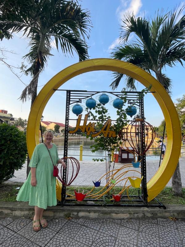 Lady standing next to a sign for Hoi An.