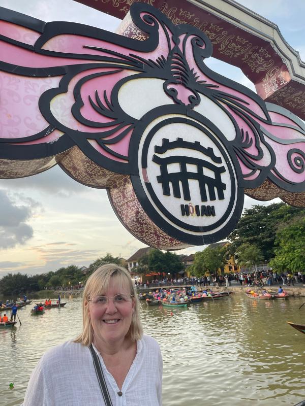 A lady in front of a Hoi An sign.